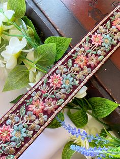 flowers and leaves are on the table next to an old box with a ribbon in it