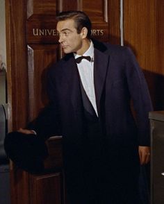 a man in a tuxedo standing next to a door