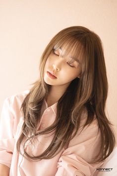 a woman with her eyes closed sitting on a bed wearing a pink shirt and white pants