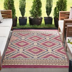 an outdoor area rug with potted plants in the background and two benches to the side