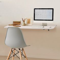 a desk with a computer and books on it, next to a wall mounted clock