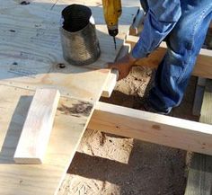 a man is using a drill to attach wood planks on the ground with a screwdriver