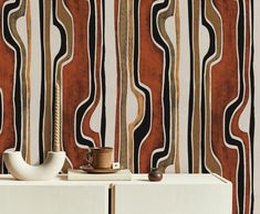 a white cabinet sitting next to a wall covered in art deco style striped wallpaper