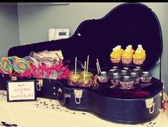 a guitar case filled with candies and lollipops sitting on top of a table