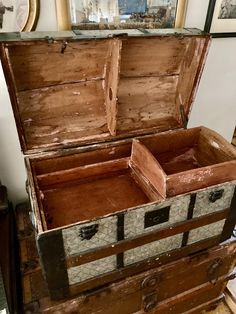 an old trunk is sitting on the floor in front of a mirror and framed pictures