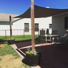 an outside patio with a table and chairs under a large shade sail on the roof