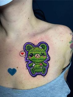 a woman with a tattoo on her chest has a teddy bear embroidered onto it's chest