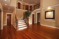 an empty living room with wood floors and stairs