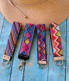 three different colored straps on a blue wooden surface with a straw hat and other items