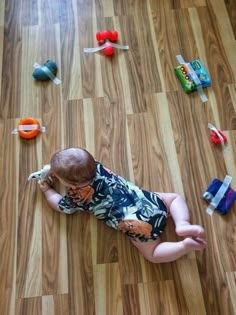 a baby laying on the floor with toys all over it's body and head