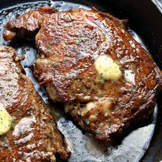 two steaks in a skillet with butter on the top and some sauce on the bottom