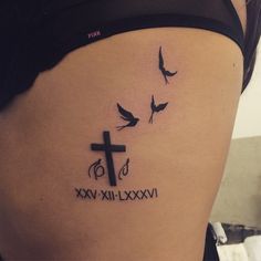 a woman's stomach with a cross and birds tattoo on her lower back side