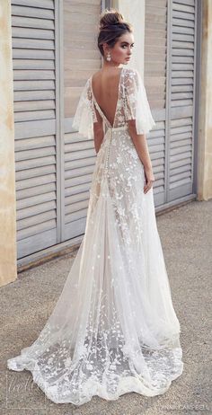 a woman in a white wedding dress standing next to a wall with shutters on it