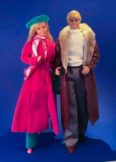 two barbie dolls are standing next to each other on a blue background, one is wearing a pink coat and the other has a green hat