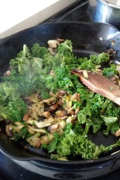 a pan filled with broccoli and mushrooms on top of a stove