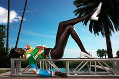 a woman laying on top of a metal rail next to palm trees