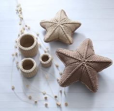 three knitted starfish ornaments on a white wooden table next to two small cups