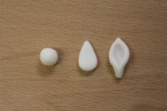 three pieces of white plastic sitting on top of a wooden table next to each other