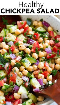 a salad with chickpeas, cucumber and tomatoes in a white bowl