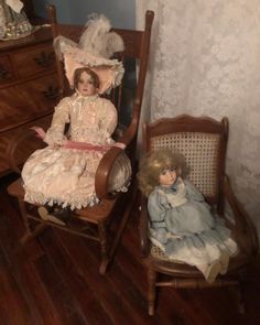 two dolls sitting on chairs in a room