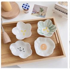 three white dishes with designs on them sitting on a wooden tray