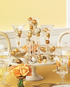 a table topped with lots of glasses filled with gold and silver decorations on top of it