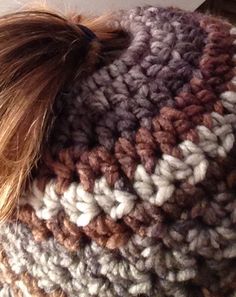 a close up of a person wearing a knitted hat with a pom - pom