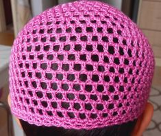 a woman wearing a pink crochet hat with black dots on it's side