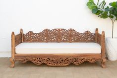 a wooden bench sitting on top of a tiled floor next to a potted plant