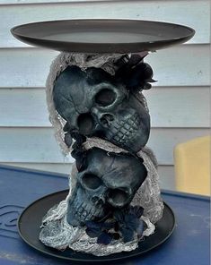 two skulls are stacked on top of each other in front of a blue table with a black plate