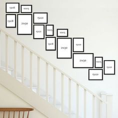 there are many frames on the wall above the stairs