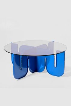 a glass table with two blue legs and a circular top that has an unusual design on it