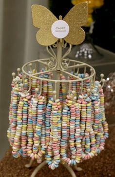 a close up of a cell phone holder made out of candy beads and gold butterfly brooch pins