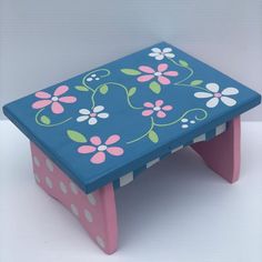 a blue and pink stool with flowers painted on it