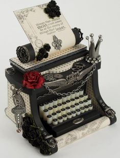 an old fashioned typewriter is decorated with black and white paper, roses, and beads