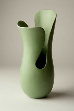 a green vase sitting on top of a white table