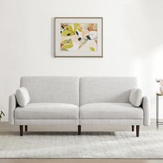 a living room with a white couch and rug on the floor next to a painting