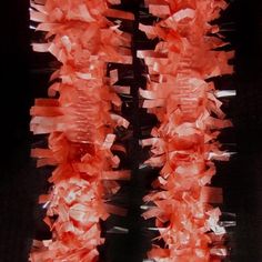 some red pieces of paper hanging from a black wall with white strips on the bottom