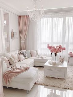 a living room filled with furniture and a chandelier hanging from the ceiling over a white coffee table