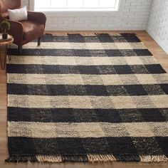 a black and white rug in a living room with a brown chair next to it