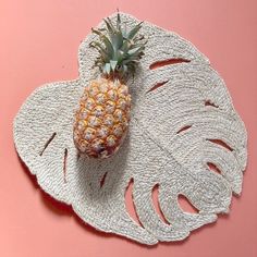 a pineapple sitting on top of a white doily next to a pink wall