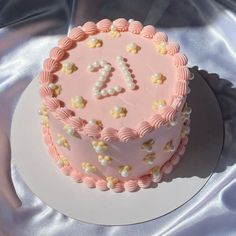 a pink birthday cake with white and yellow decorations