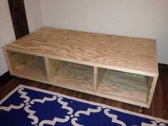 a wooden entertainment center sitting on top of a blue and white rug in a living room