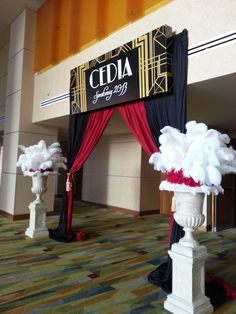 an event with red and black draping, white vases filled with flowers and feathers