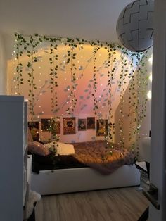 a bedroom decorated in white and green with plants growing on the wall, lights hanging from the ceiling