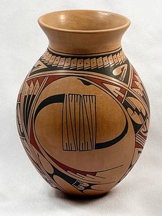 a brown and black vase sitting on top of a white table