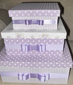 three boxes stacked on top of each other with purple bows and polka dot designs in them