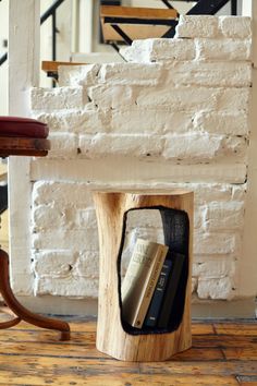 there is a wooden book holder with books in it on the floor next to a brick wall