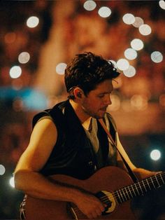 a man playing an acoustic guitar on stage