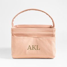 a pink bag with the letters akl on it and a brown handle is shown